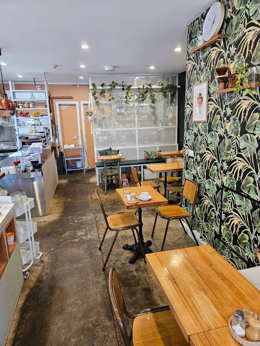 Inside Battle café: sunlit timber tables beside its leafy feature wall